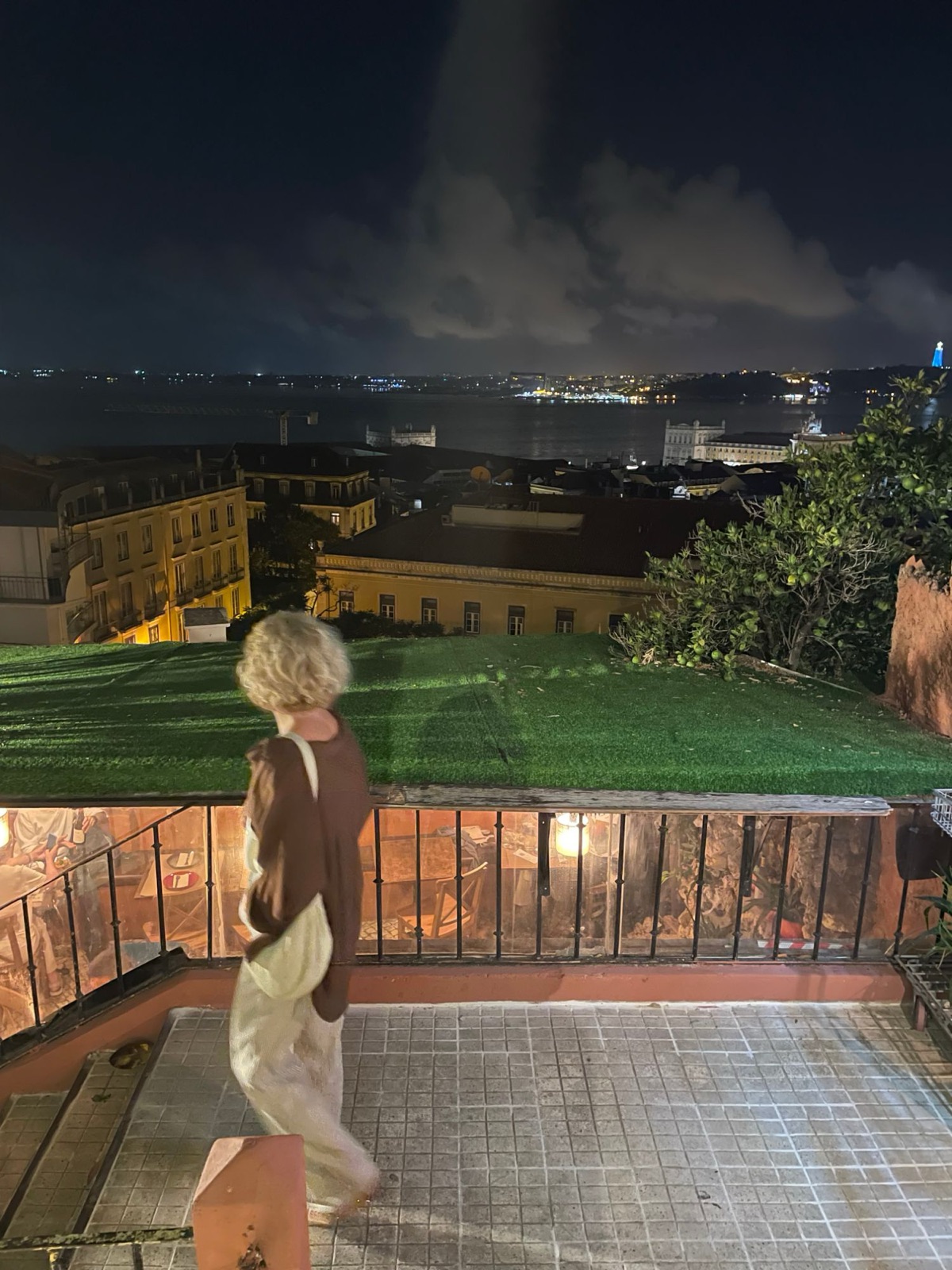 O rio e as luzes de Lisboa vistos de um terraço à noite
