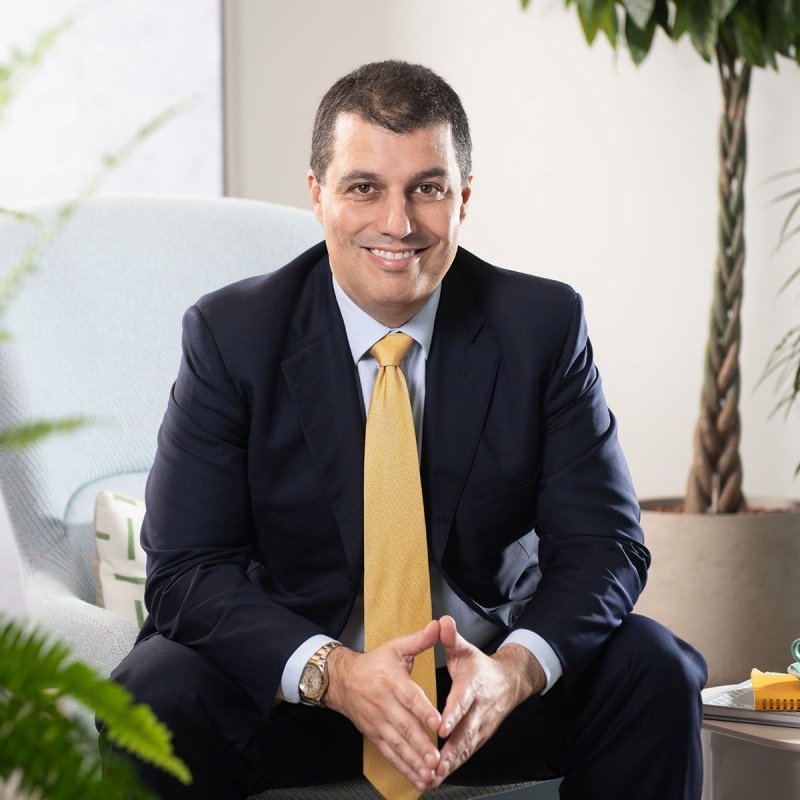 Roberto Varandas, smiling, in a dark suit with a yellow tie