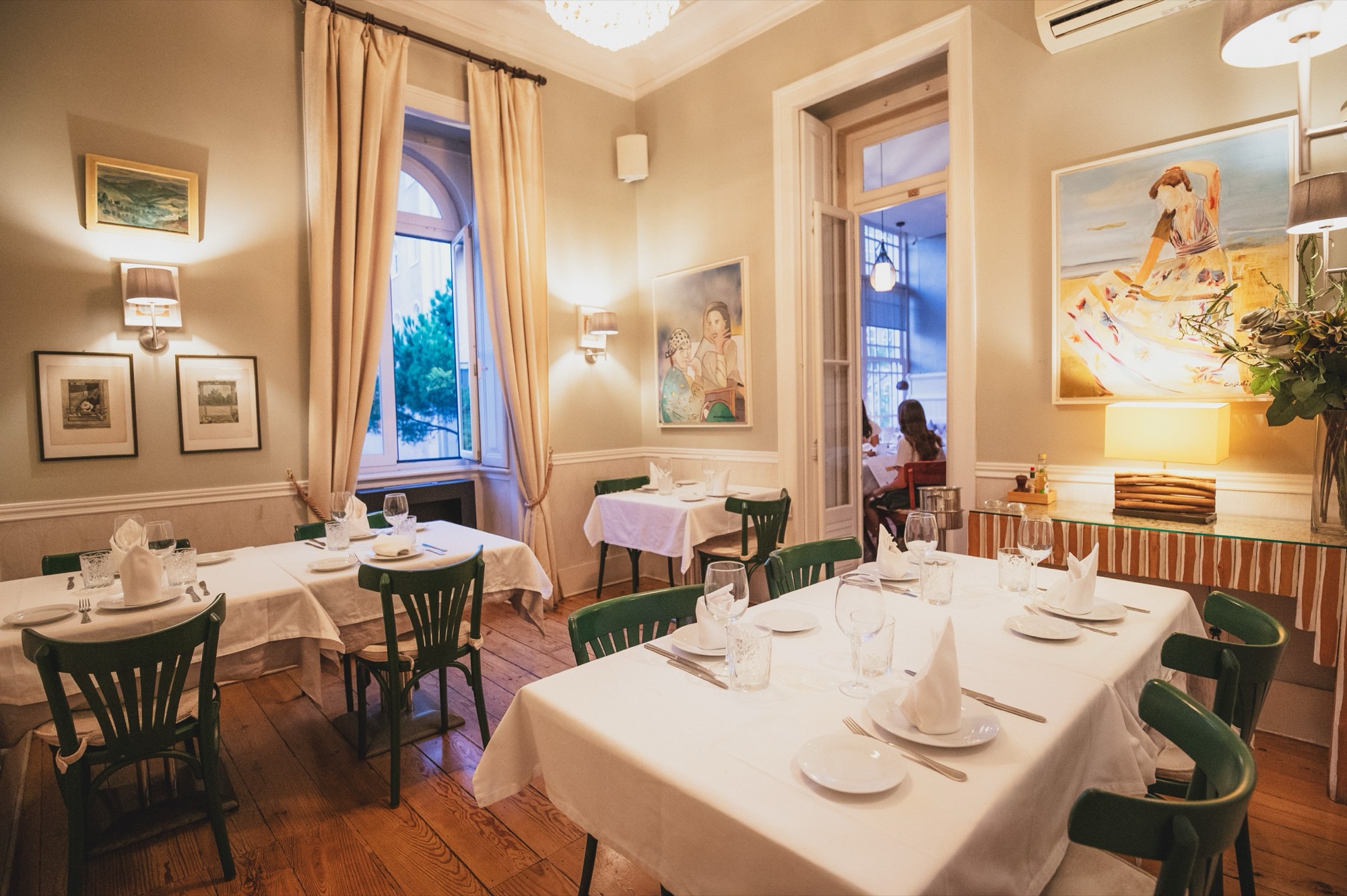 Uma mesa posta junto a um candeeiro de pé e cortinados altos na Villa Sabóia